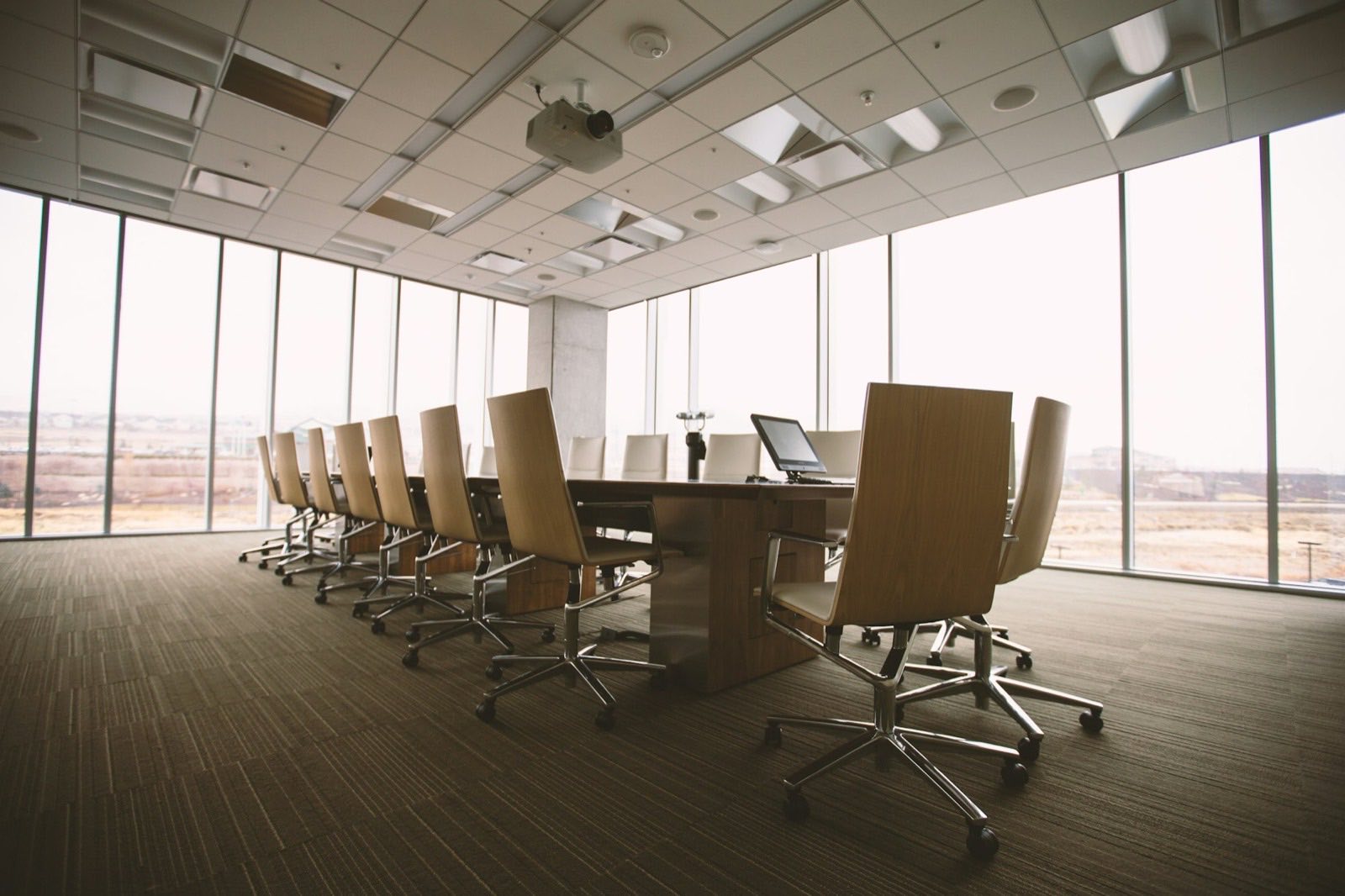 A bright training room with a long table, chairs, and ceiling projector